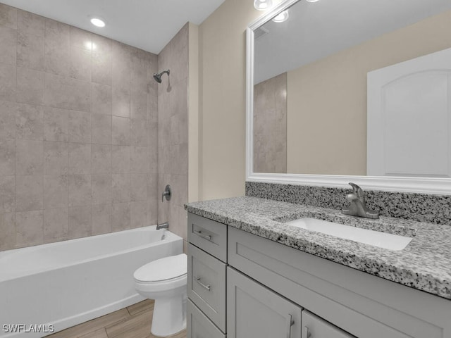 full bathroom with vanity, toilet, wood-type flooring, and tiled shower / bath