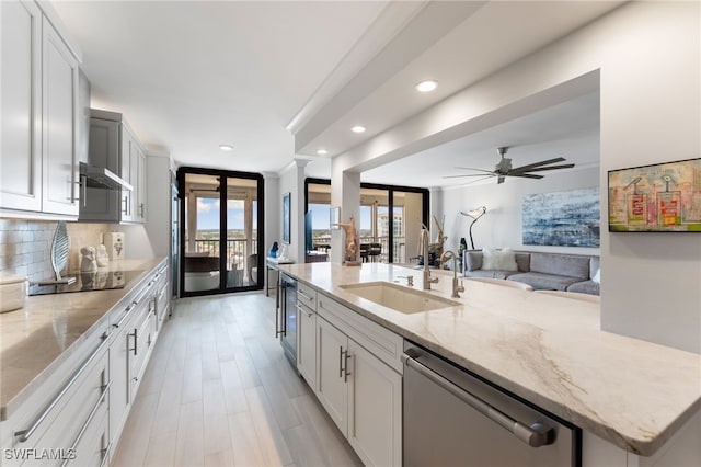 kitchen featuring light stone countertops, black electric stovetop, stainless steel dishwasher, sink, and white cabinetry