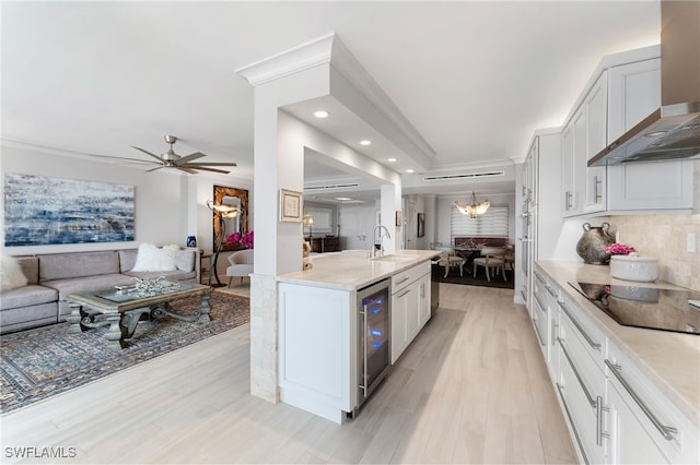 kitchen featuring white cabinetry, wall chimney range hood, wine cooler, black electric stovetop, and light wood-type flooring