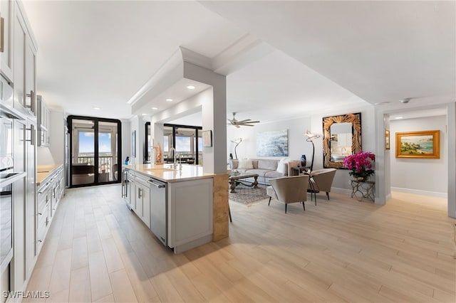 kitchen with dishwasher, white cabinets, a center island with sink, ceiling fan, and light hardwood / wood-style floors