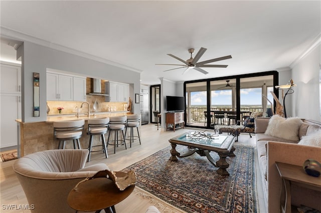 living room featuring ceiling fan, light wood-type flooring, and ornamental molding