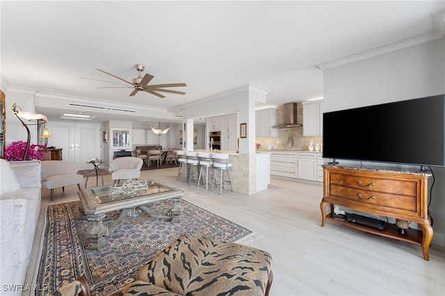 living room with ceiling fan, ornamental molding, and light hardwood / wood-style flooring