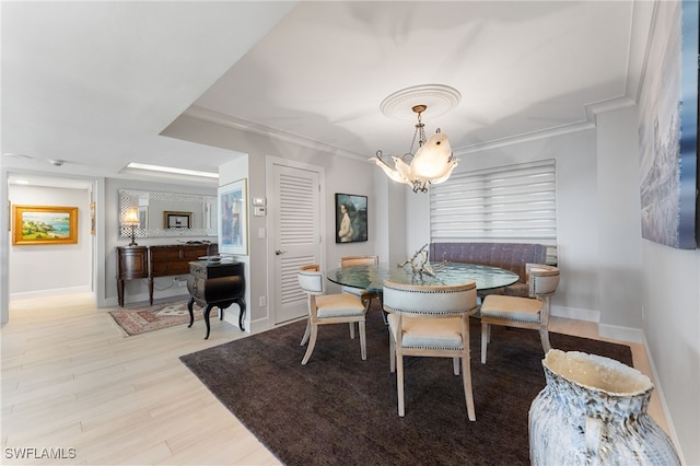 dining area with light wood-type flooring, a notable chandelier, and ornamental molding