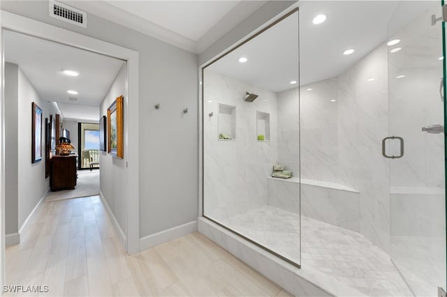 bathroom featuring a shower with door and crown molding