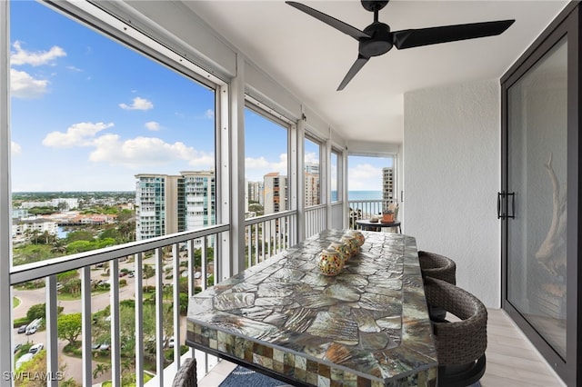 sunroom / solarium with a water view and ceiling fan