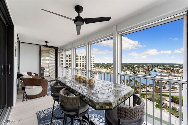 sunroom featuring ceiling fan and a water view