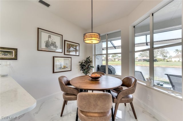 dining room with a water view, baseboards, visible vents, and marble finish floor