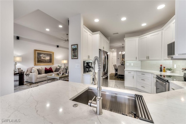 kitchen featuring tasteful backsplash, light stone counters, recessed lighting, appliances with stainless steel finishes, and white cabinets