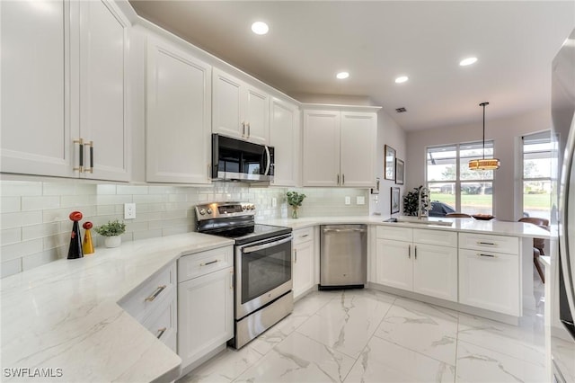 kitchen with a sink, backsplash, stainless steel appliances, a peninsula, and white cabinets