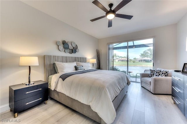 bedroom with lofted ceiling, a water view, light wood-style floors, and access to outside