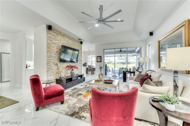 living room featuring marble finish floor, a raised ceiling, and ceiling fan