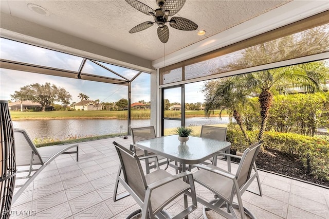 sunroom / solarium featuring a ceiling fan and a water view