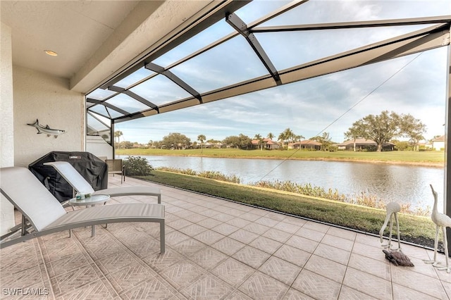 view of patio / terrace with glass enclosure and a water view