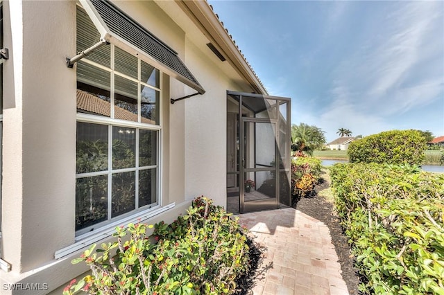 view of home's exterior with a lanai, stucco siding, and a water view