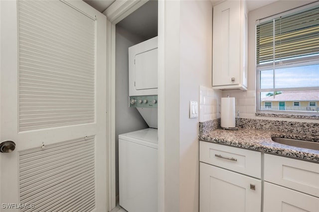 clothes washing area featuring sink and stacked washer and dryer