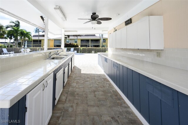 kitchen featuring white cabinets, backsplash, blue cabinetry, and sink