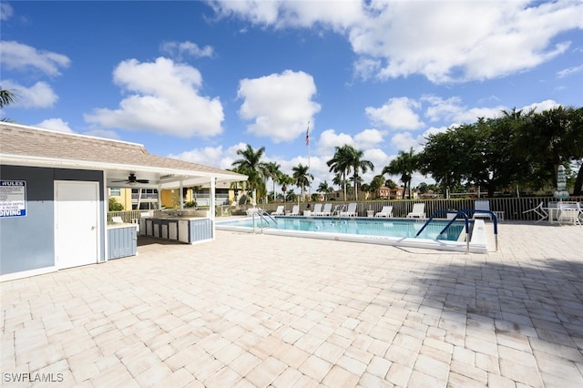 view of pool with ceiling fan, a patio, and an outdoor kitchen