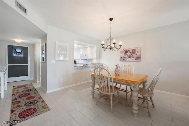 dining room with light hardwood / wood-style flooring and an inviting chandelier