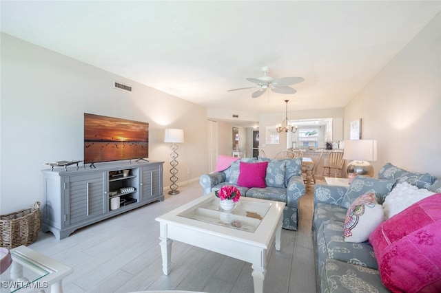 living room with hardwood / wood-style floors and ceiling fan with notable chandelier