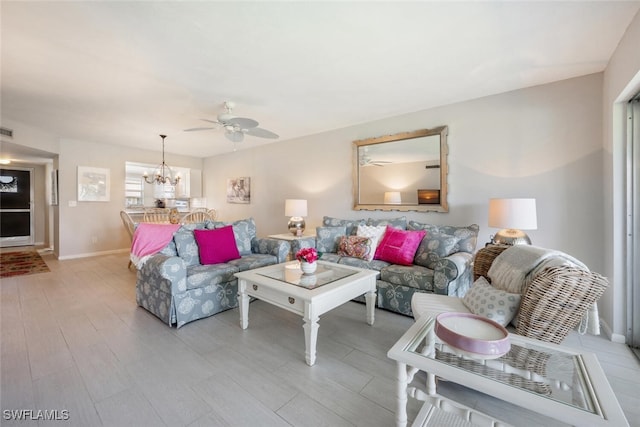 living room featuring ceiling fan with notable chandelier and light hardwood / wood-style floors