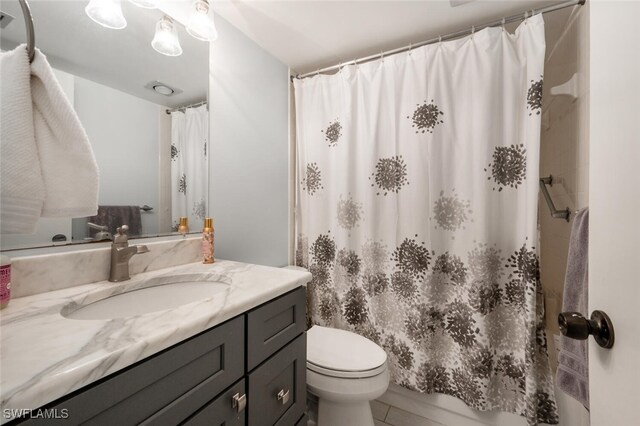 bathroom with tile patterned floors, vanity, curtained shower, and toilet