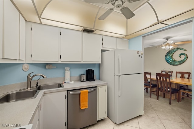 kitchen featuring sink, light tile patterned floors, stainless steel dishwasher, white fridge, and white cabinets