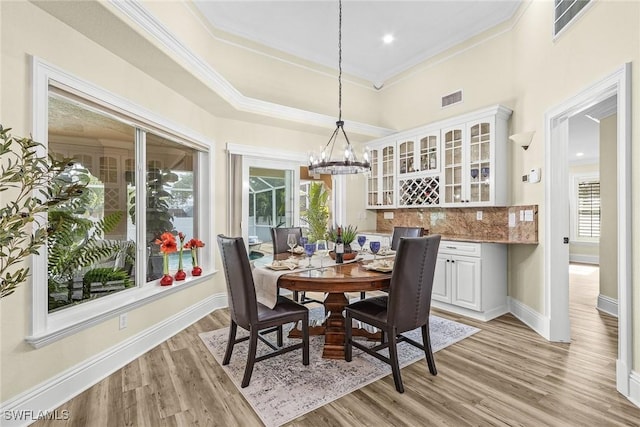 dining area featuring a chandelier, light wood-type flooring, and ornamental molding