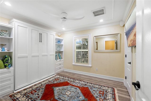 bedroom featuring light wood-type flooring, a closet, ceiling fan, and crown molding