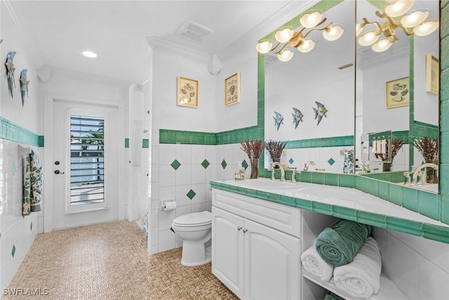 bathroom with crown molding, vanity, tile walls, and toilet