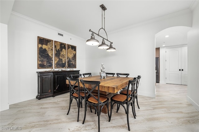 dining area featuring light wood-type flooring and crown molding