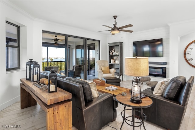 living room featuring a fireplace, light wood-type flooring, ceiling fan, and crown molding