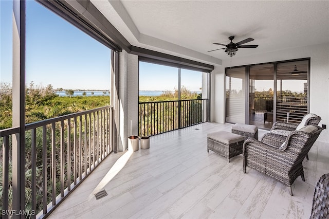 sunroom / solarium with a water view and ceiling fan