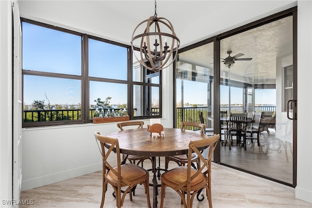 dining room with ceiling fan with notable chandelier and light wood-type flooring