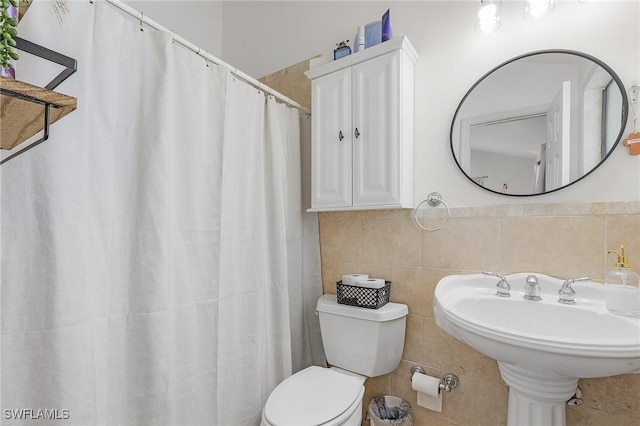 full bath featuring a wainscoted wall, a sink, toilet, and tile walls