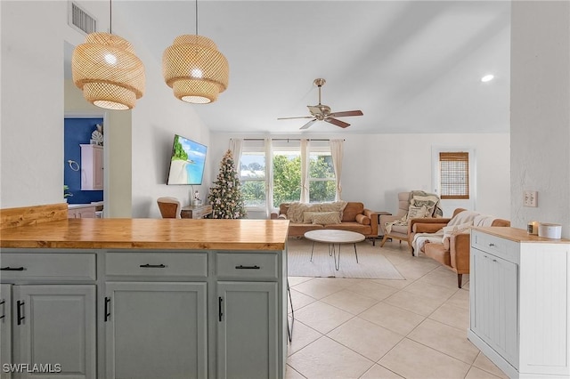 kitchen with lofted ceiling, light tile patterned floors, visible vents, a ceiling fan, and open floor plan