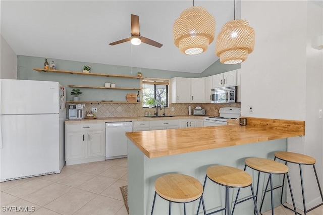 kitchen with white appliances, decorative backsplash, a peninsula, white cabinetry, and a sink