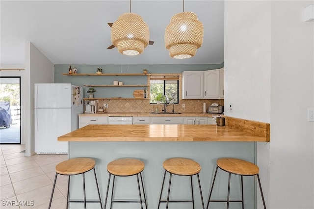 kitchen with white appliances, backsplash, a sink, and a kitchen breakfast bar