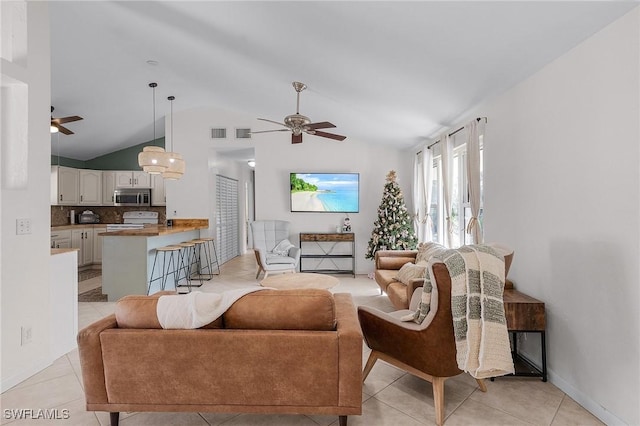 living area with lofted ceiling, light tile patterned floors, and ceiling fan