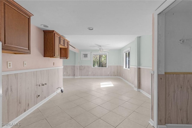 unfurnished room featuring wainscoting, a ceiling fan, and wooden walls