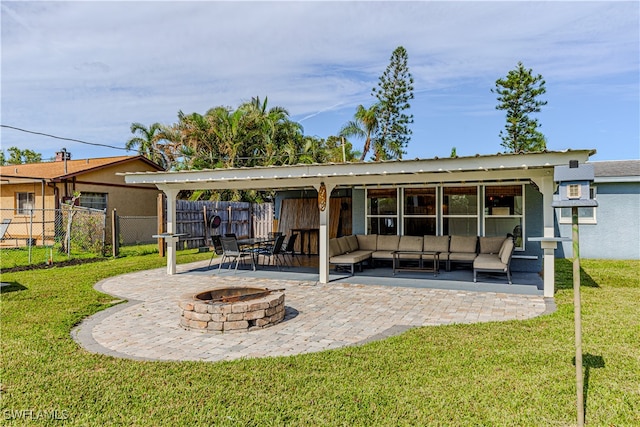 back of property with a lawn, a patio area, and an outdoor living space with a fire pit