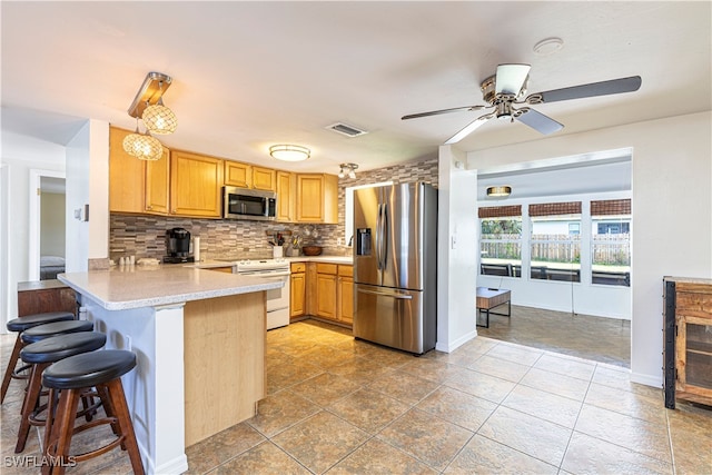 kitchen with ceiling fan, a kitchen breakfast bar, tasteful backsplash, kitchen peninsula, and appliances with stainless steel finishes