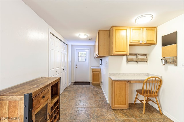 kitchen with a kitchen bar and light brown cabinetry