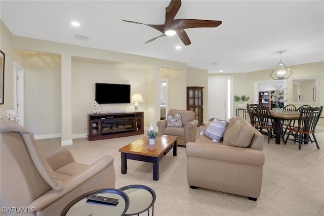 tiled living room with ceiling fan with notable chandelier