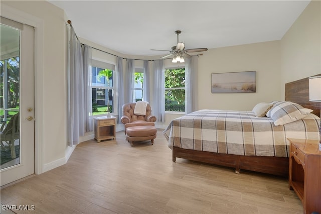 bedroom featuring ceiling fan, access to exterior, light hardwood / wood-style flooring, and multiple windows