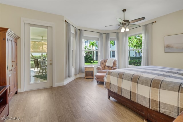 bedroom featuring access to outside, light hardwood / wood-style flooring, multiple windows, and ceiling fan