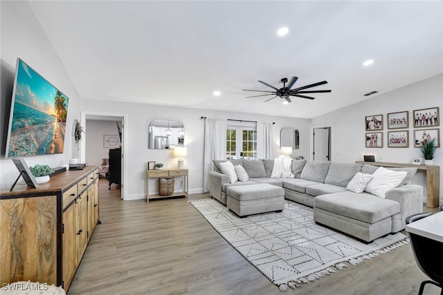 living room featuring light wood-type flooring, vaulted ceiling, and ceiling fan