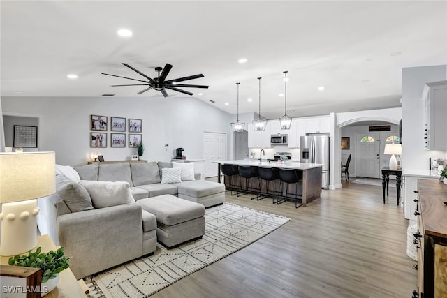 living room with light hardwood / wood-style flooring, ceiling fan, lofted ceiling, and sink