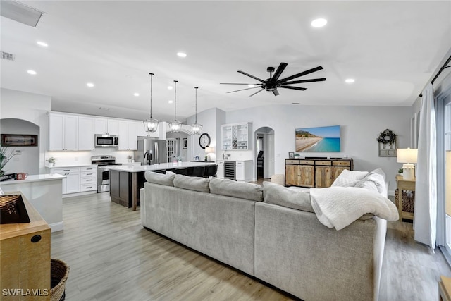 living room with ceiling fan, lofted ceiling, and light wood-type flooring