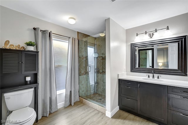 bathroom featuring hardwood / wood-style floors, vanity, a shower with shower door, and toilet