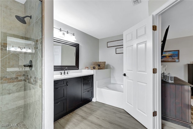 bathroom with hardwood / wood-style floors, vanity, and plus walk in shower